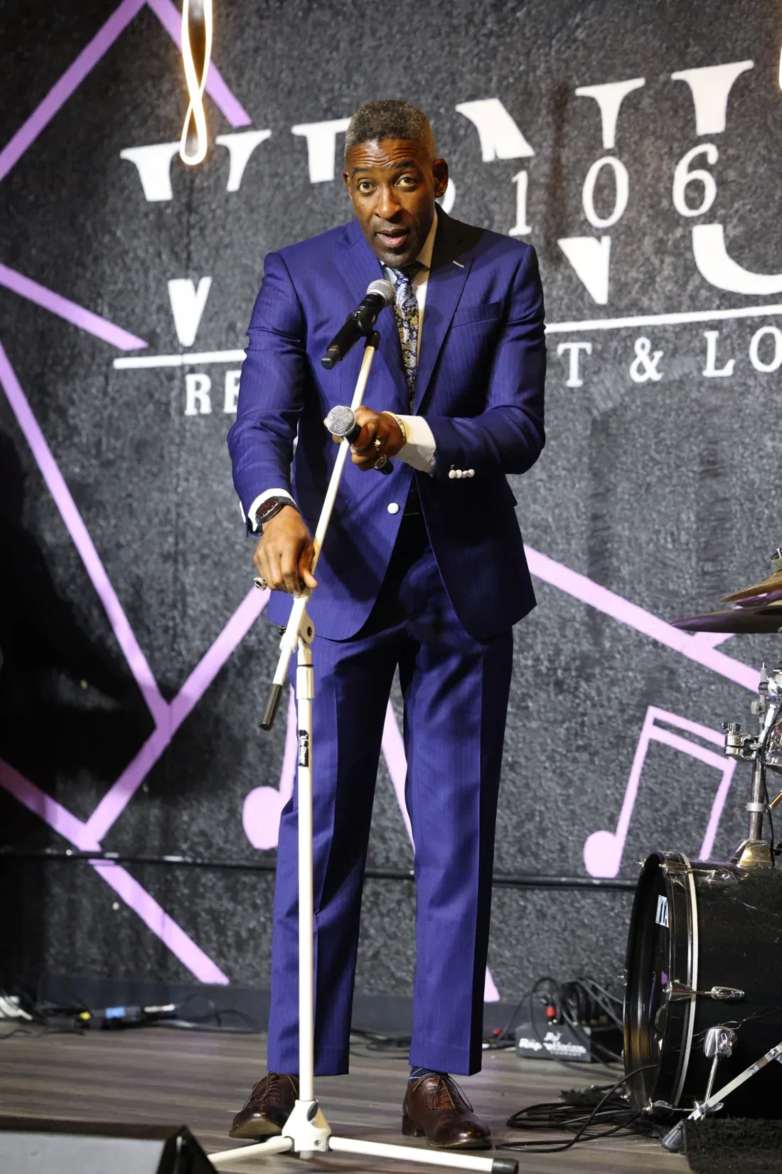 Speaker wearing a vibrant blue tailored suit onstage
