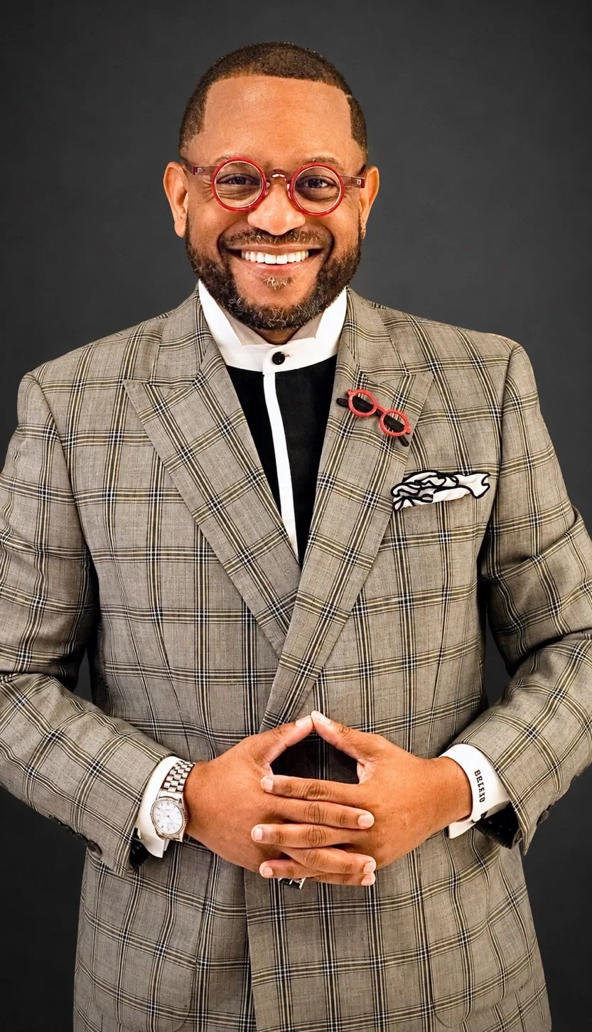 Dr. Johnson smiling in a tailored plaid suit and red eyeglasses